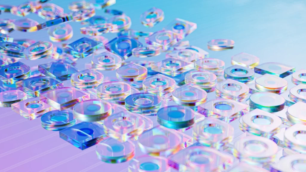 A collection of transparent, iridescent geometric shapes—cylinders, squares, and circles—scattered across a smooth, gradient blue and purple surface evokes the innovative essence of Parametric Architectural Design as they reflect light and create colorful highlights.